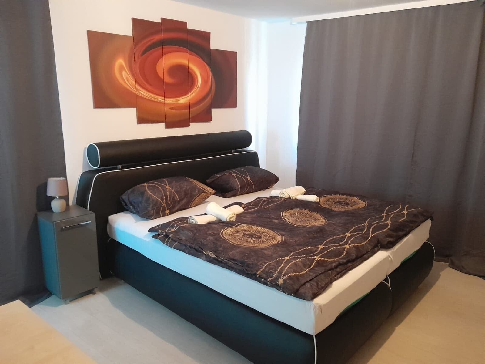 Schlafzimmer mit Spiral-Kunstwerk und blauer Bettwäsche