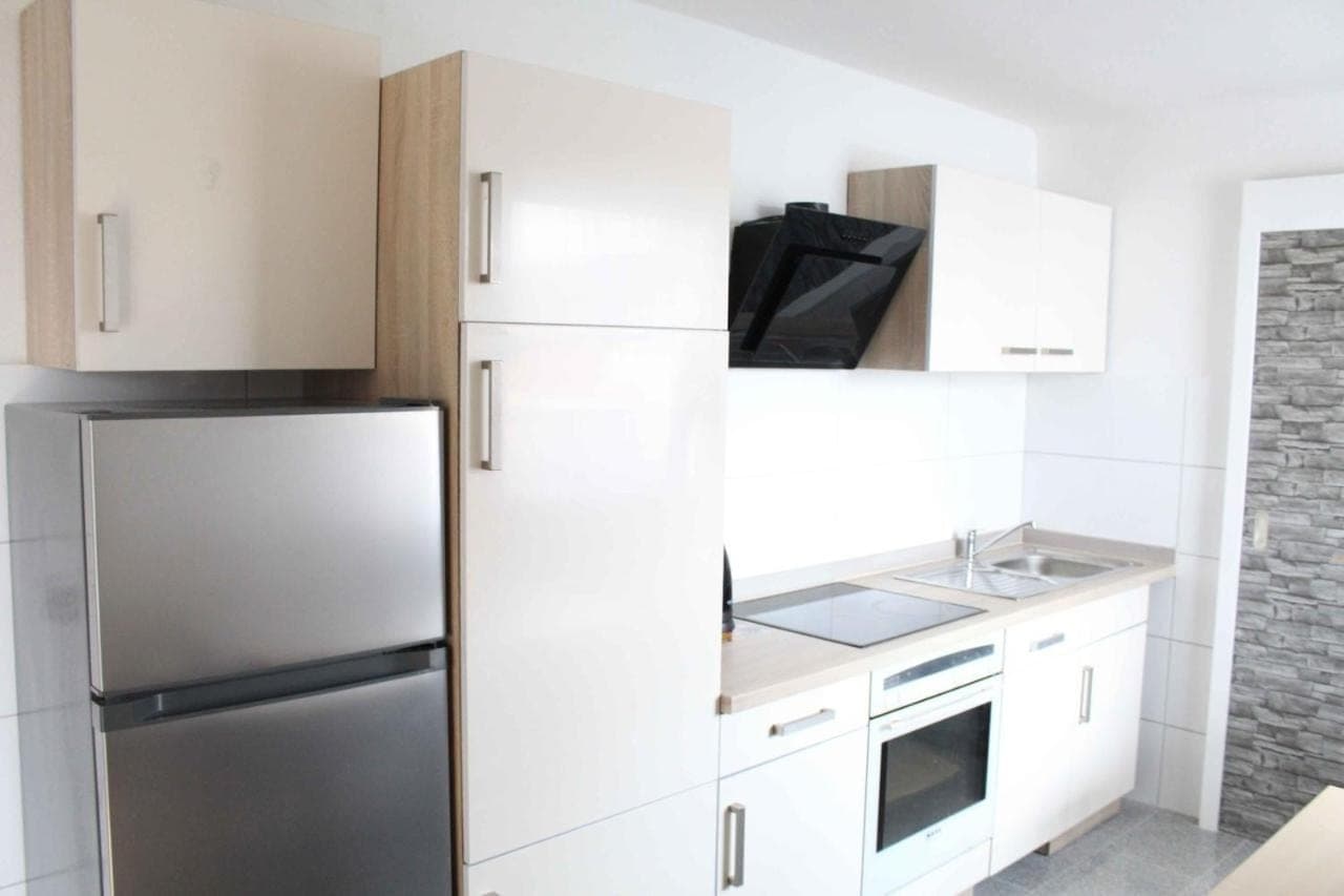 Weiße Küche mit Kühlschrank, Herd und Backofen